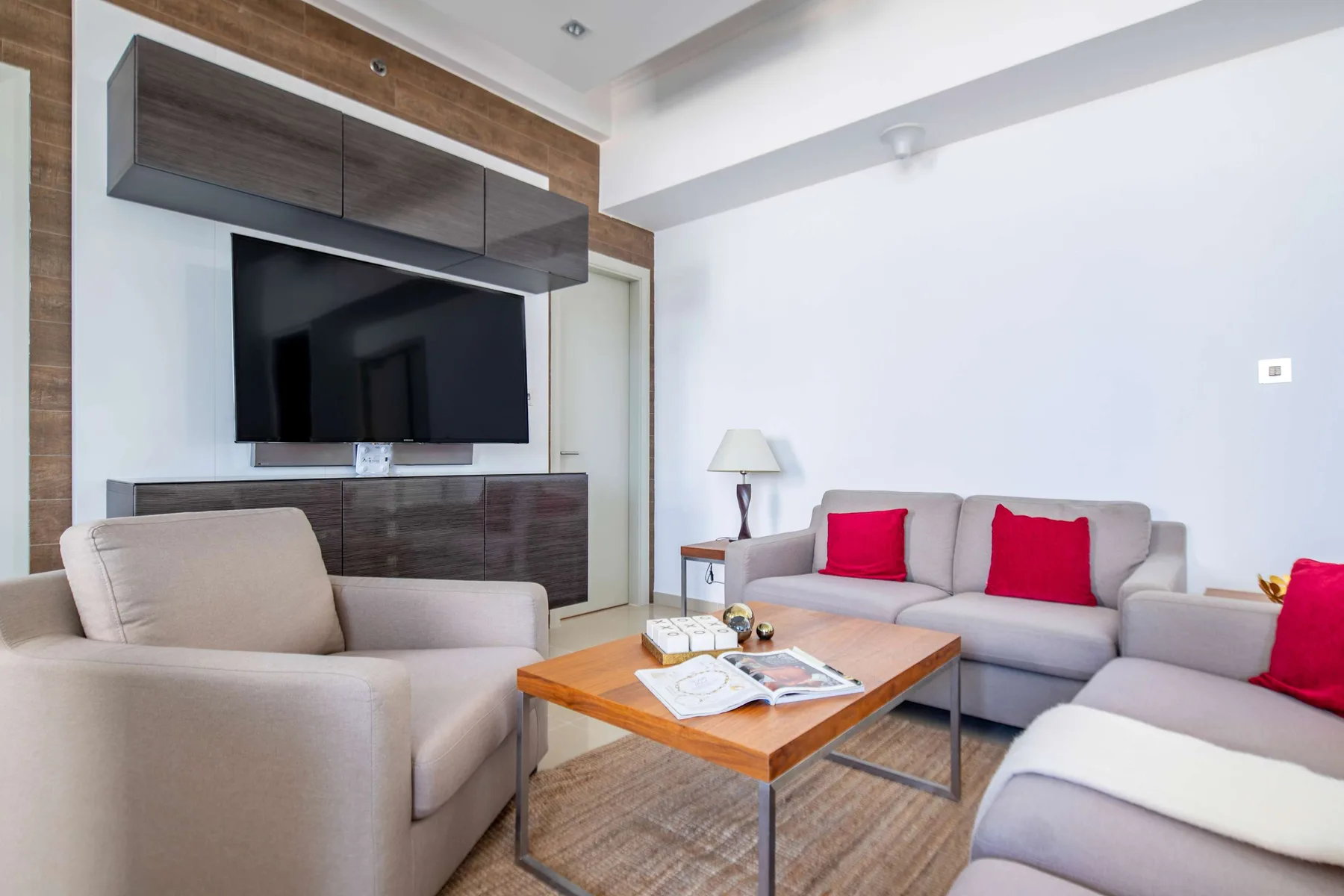 Living room with light-colored seating, a television, and a wooden coffee table.