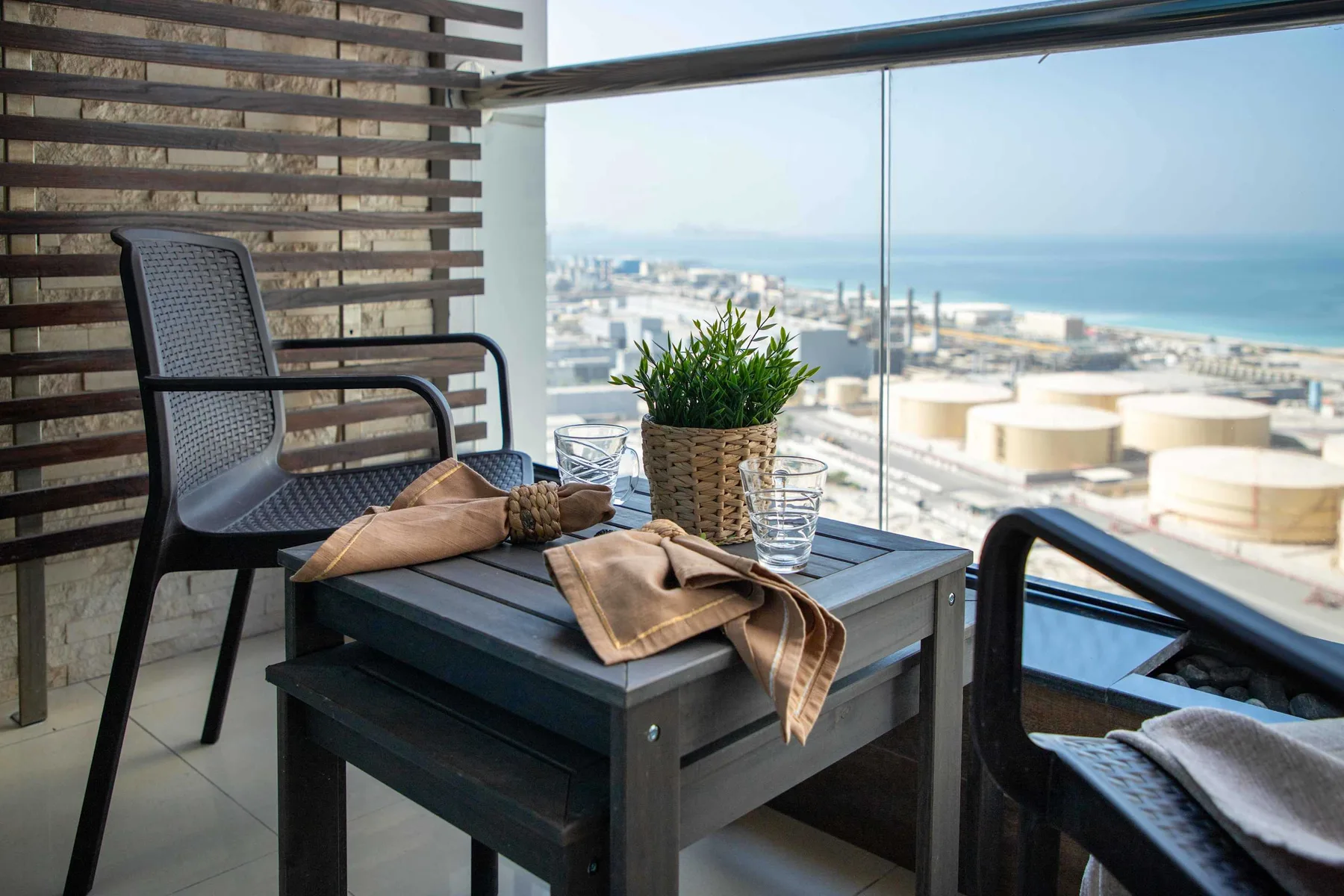 A balcony seating area with a small table and a view of the sea.