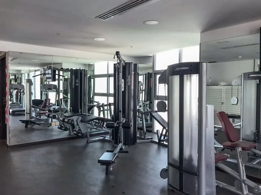 A gym with weight machines and exercise equipment in front of mirrored walls.