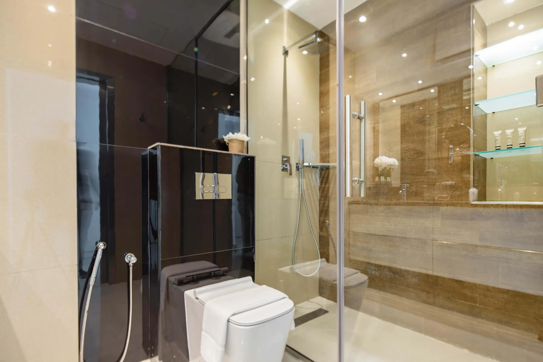 A modern bathroom with a glass-enclosed shower and a toilet.