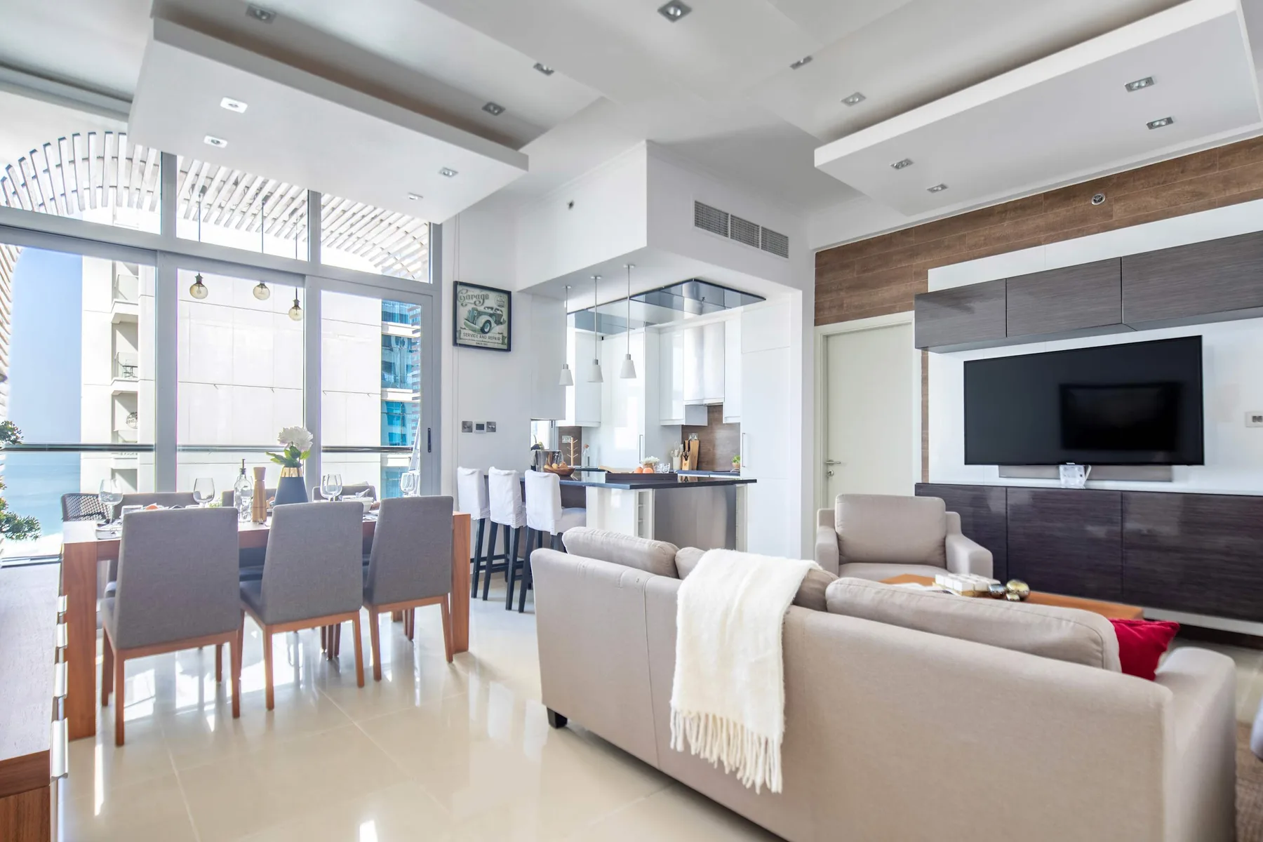 A bright open-plan living and dining area with seating and a television.