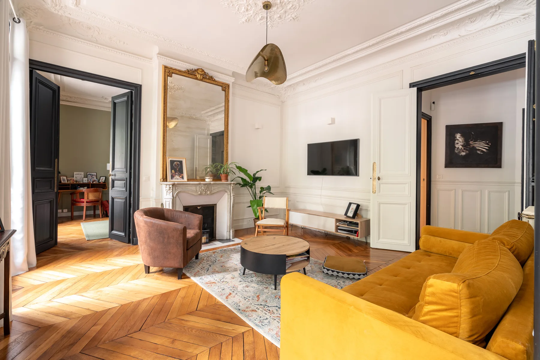 Una sala luminosa cuenta con asientos, un televisor en la pared y suelo de parquet.