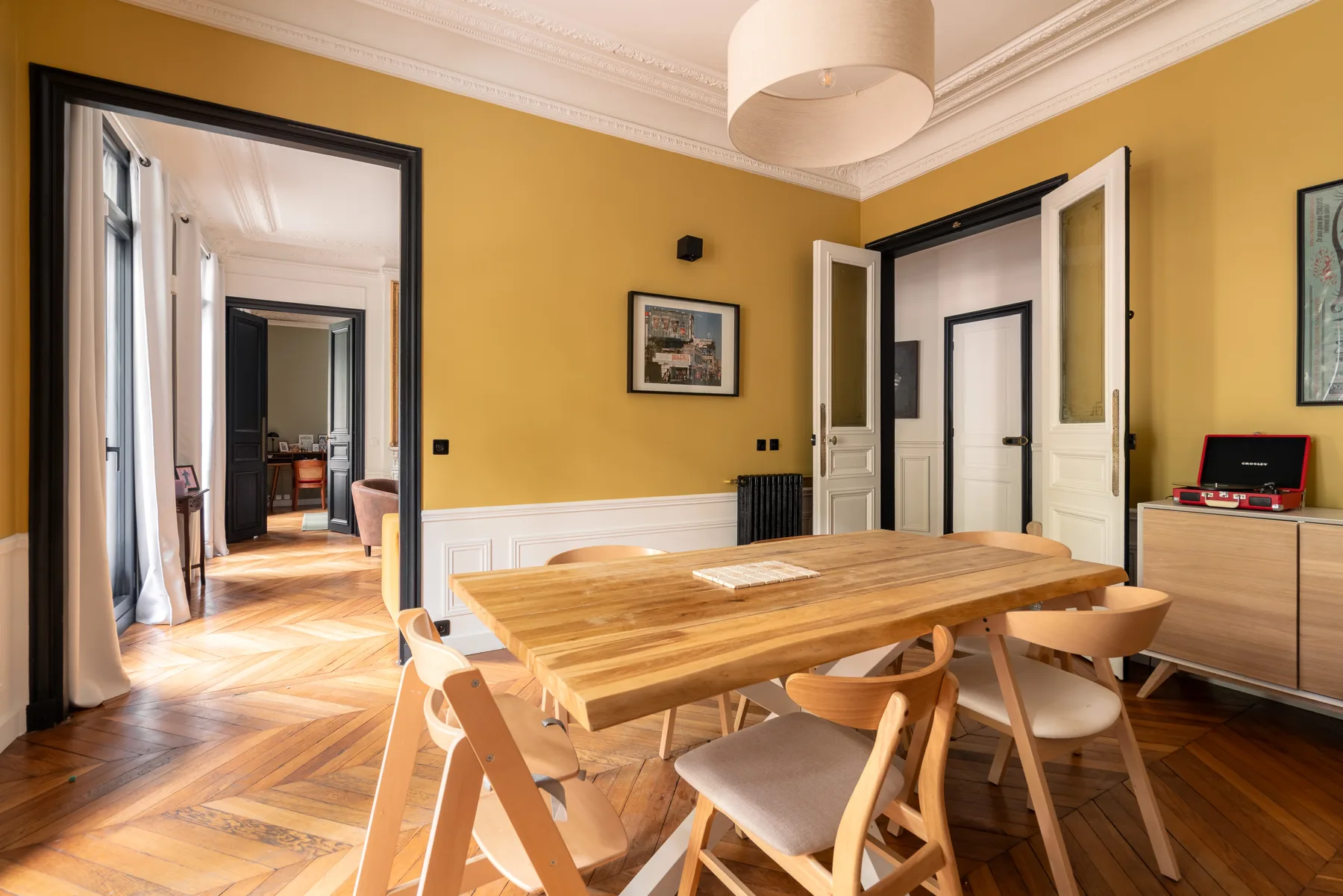 Un comedor con una mesa de madera y sillas bajo una lámpara colgante.