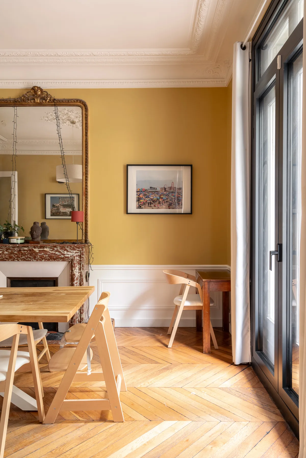 Un comedor con una mesa de madera, sillas y ventanas altas.