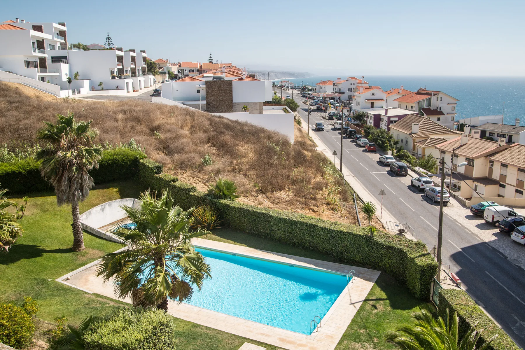 Una piscina está en un jardín ajardinado con vistas a un barrio costero.