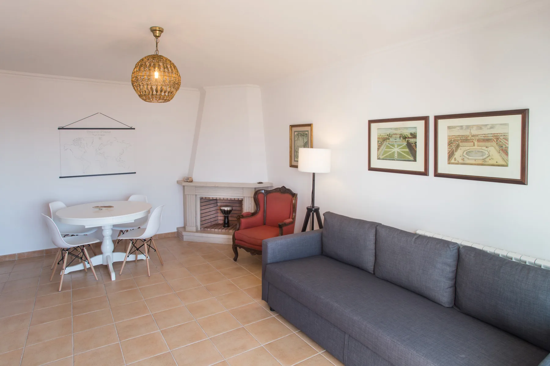 Sala de estar con un sofá gris, una mesa de comedor y una chimenea.