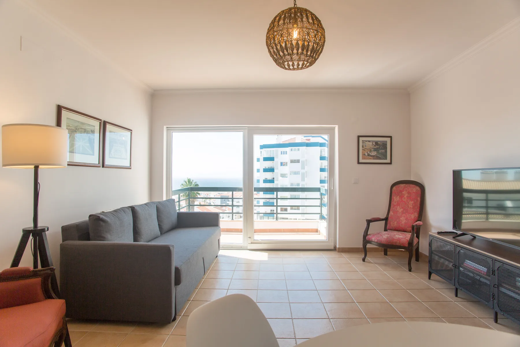 Una sala luminosa con asientos y una puerta corrediza de vidrio que da a un balcón.