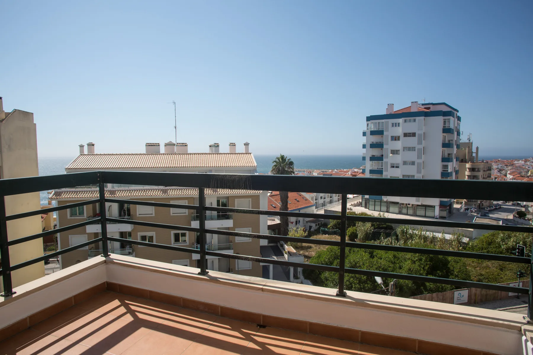 Un balcón ofrece vistas de edificios cercanos y del océano al fondo.