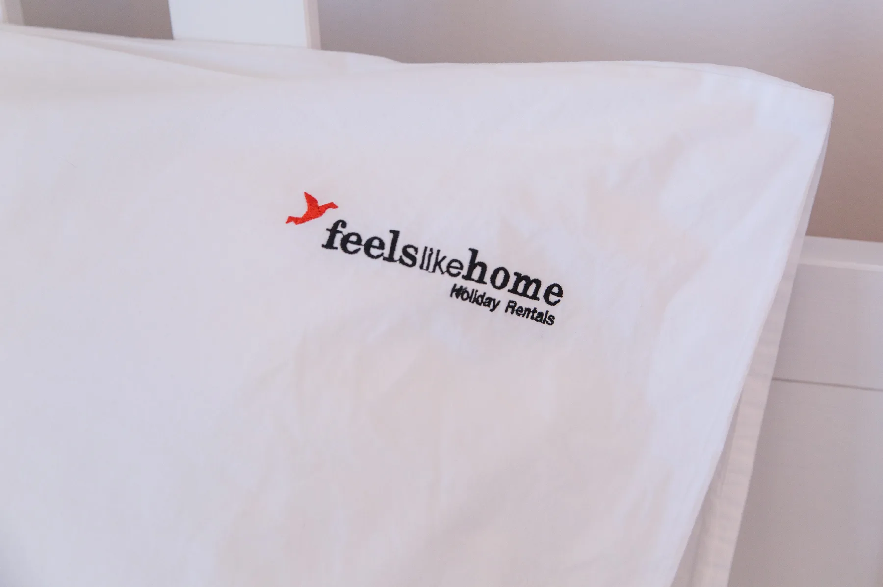 Una toalla blanca con un pequeño logotipo está extendida sobre una cama.