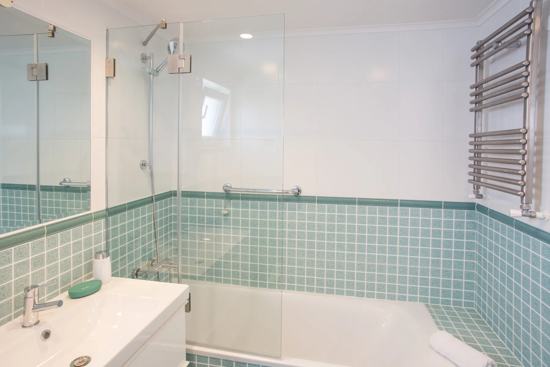 Un baño con bañera, ducha y paredes alicatadas.