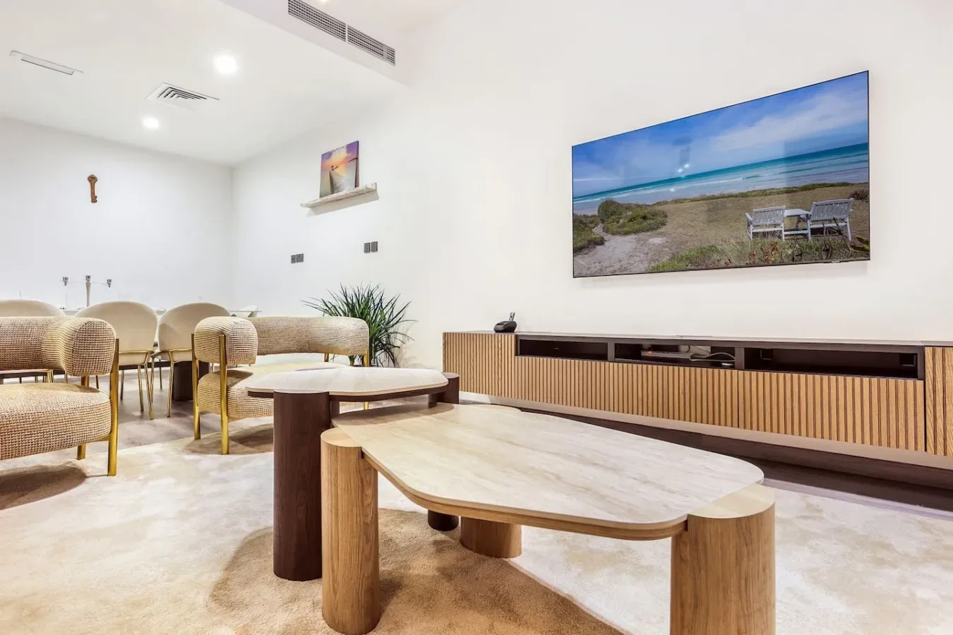 Una sala luminosa con asientos tejidos, mesas de madera y una gran imagen de playa en la pared.