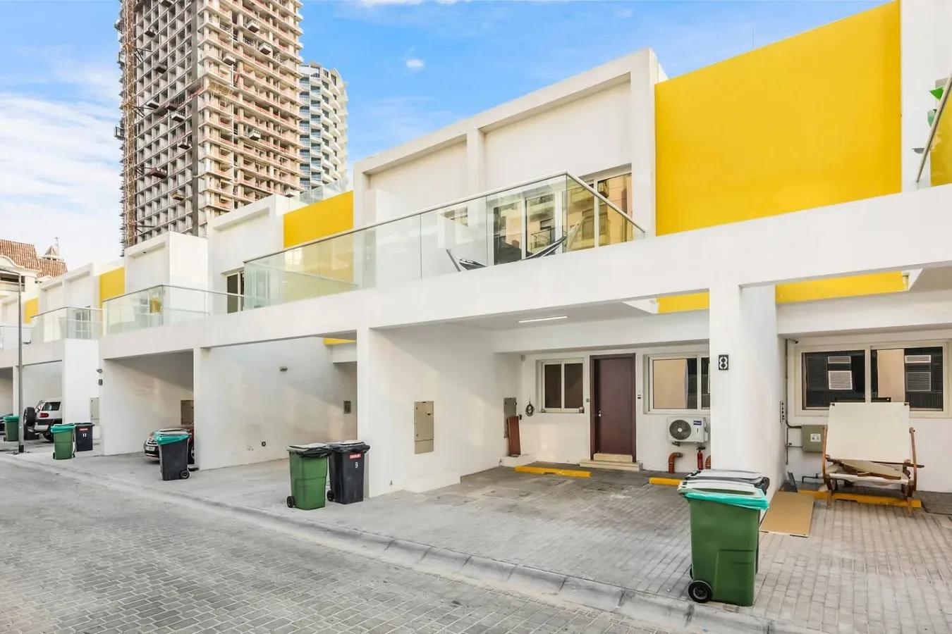 Una fila de casas modernas con balcones y una zona de estacionamiento pavimentada.