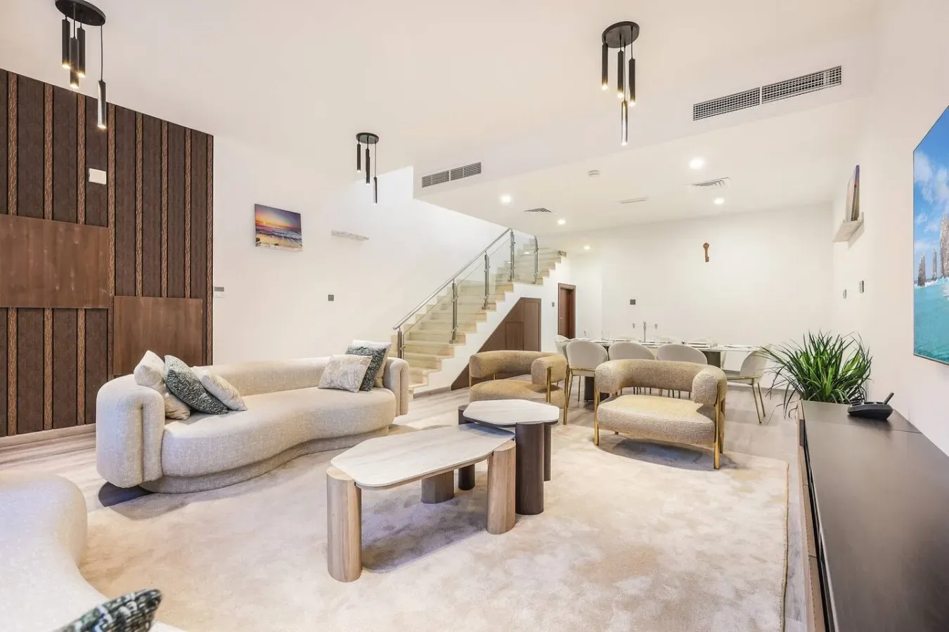 Una sala de estar luminosa con asientos, mesas bajas y una escalera.