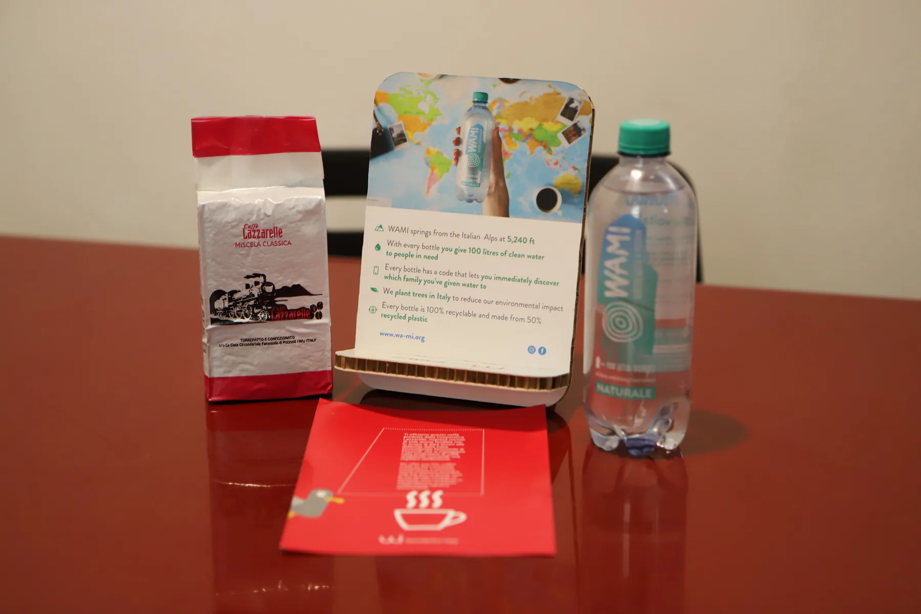 Una exhibición sobre una mesa muestra agua embotellada, un paquete de papel y una tarjeta informativa.