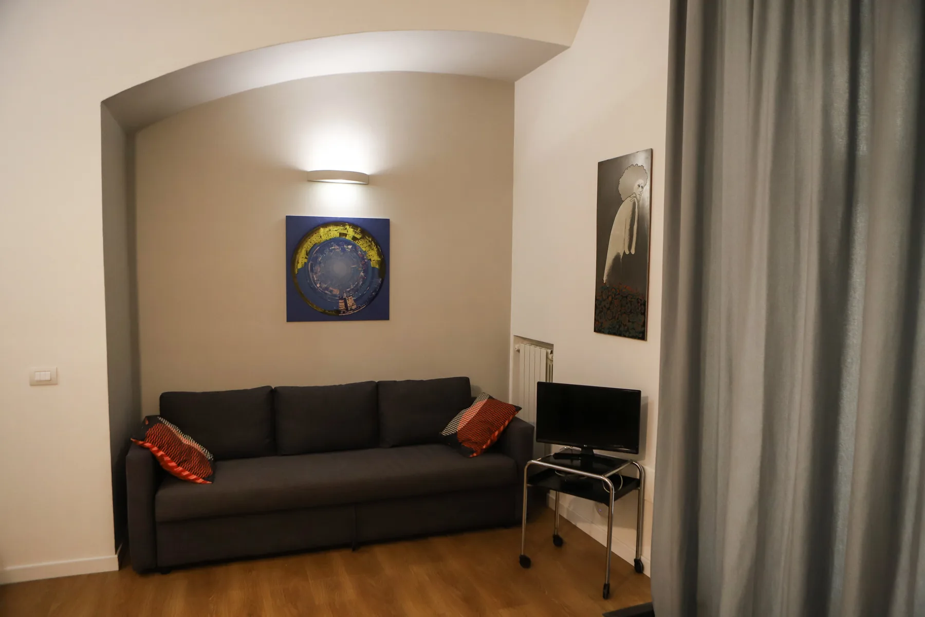 Una sala de estar con asientos oscuros, un televisor y cortinas.