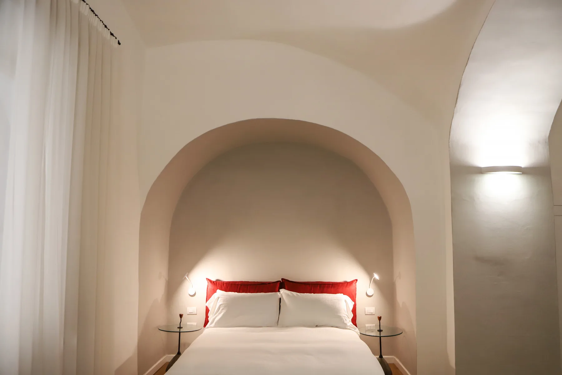 Un dormitorio con una cama en un nicho de pared arqueado.