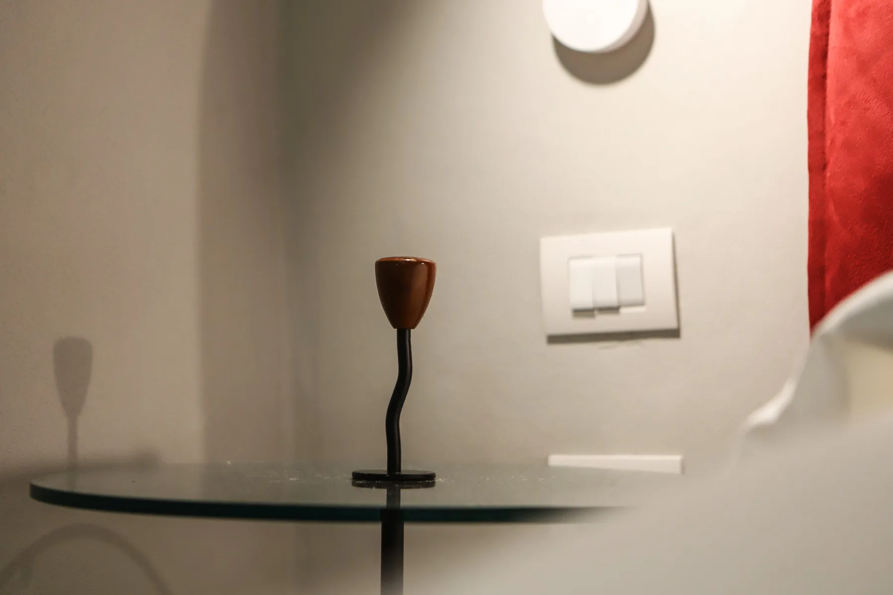 Una pequeña repisa de pared con una vela está debajo de un interruptor.