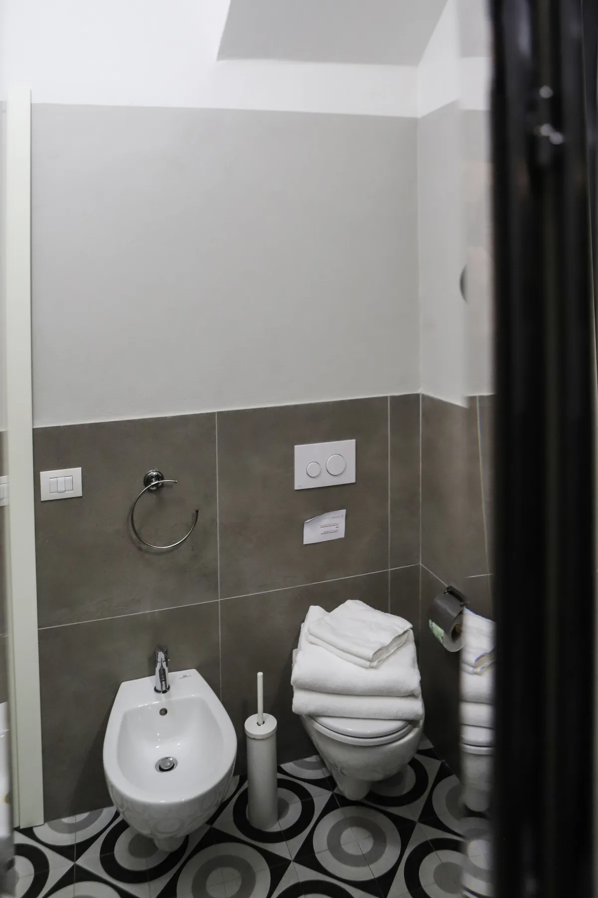 Un baño alicatado con inodoro, bidé y suelo estampado.