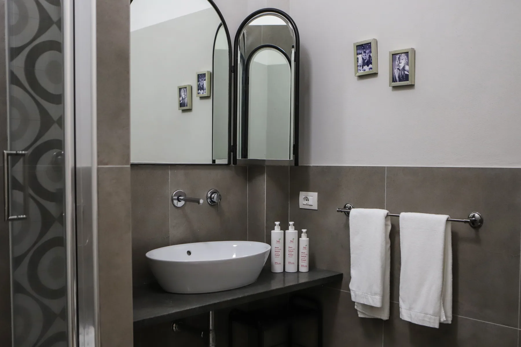 Un tocador de baño con lavabo sobre encimera, espejo de pared y toallas en una barra.