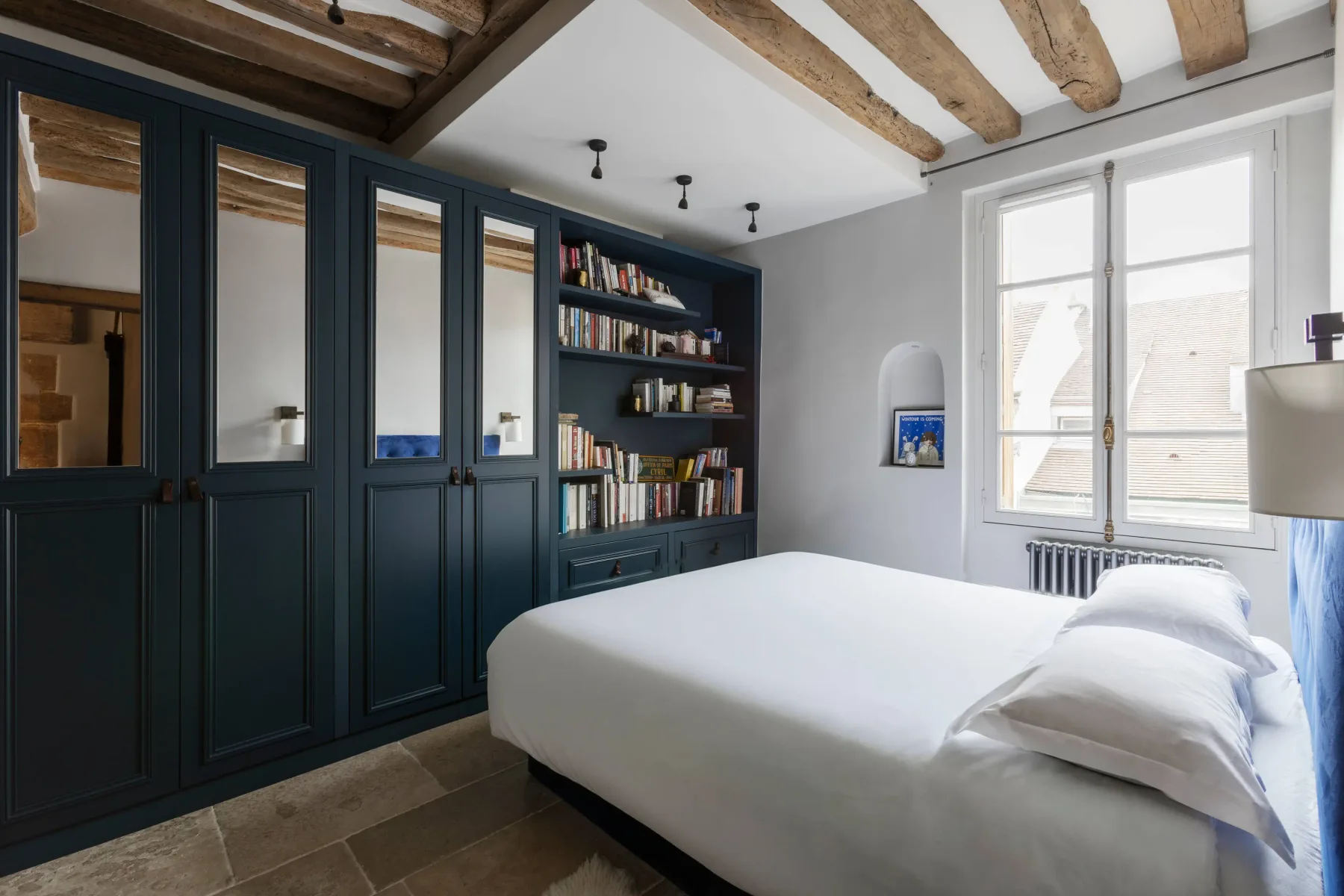 Dormitorio con una cama junto a armarios oscuros empotrados y estanterías.