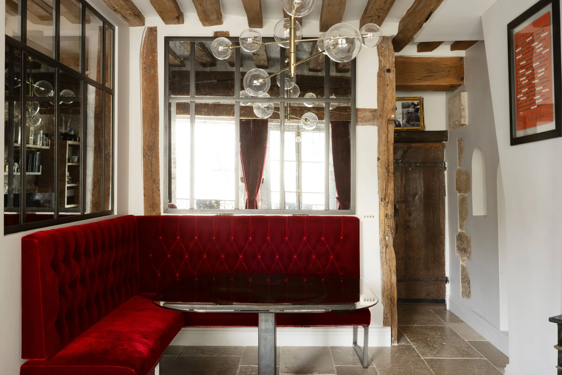 Un comedor con asientos tapizados rojos, una mesa y vigas de madera expuestas en el techo.