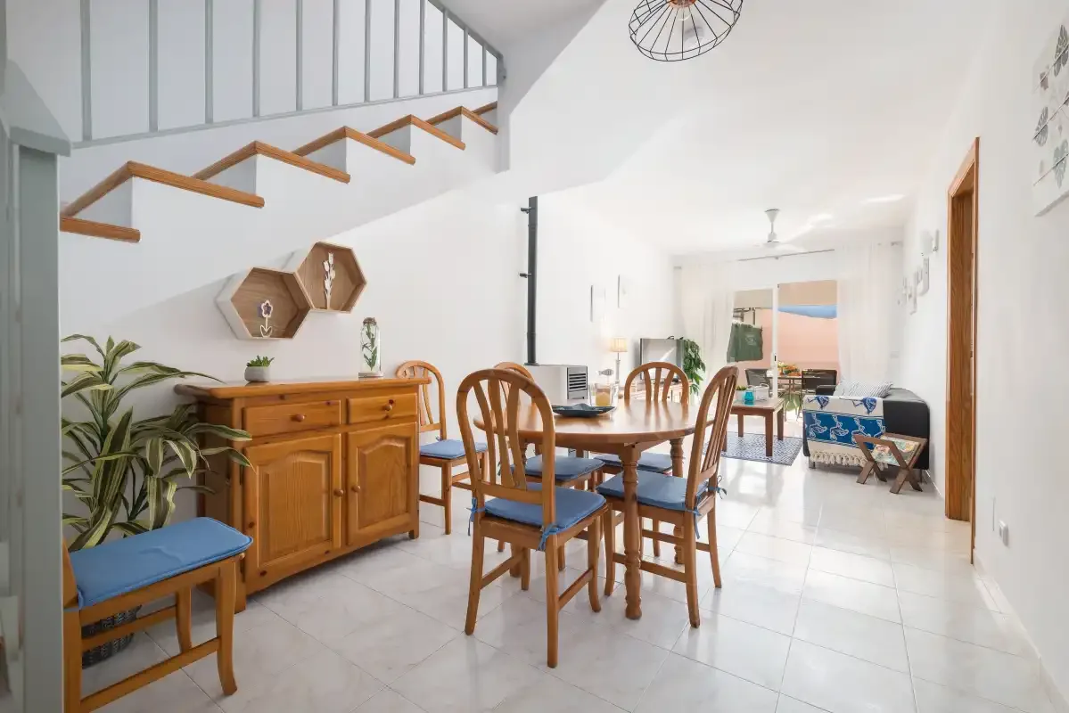 A bright dining area with wooden seating beneath an open staircase.