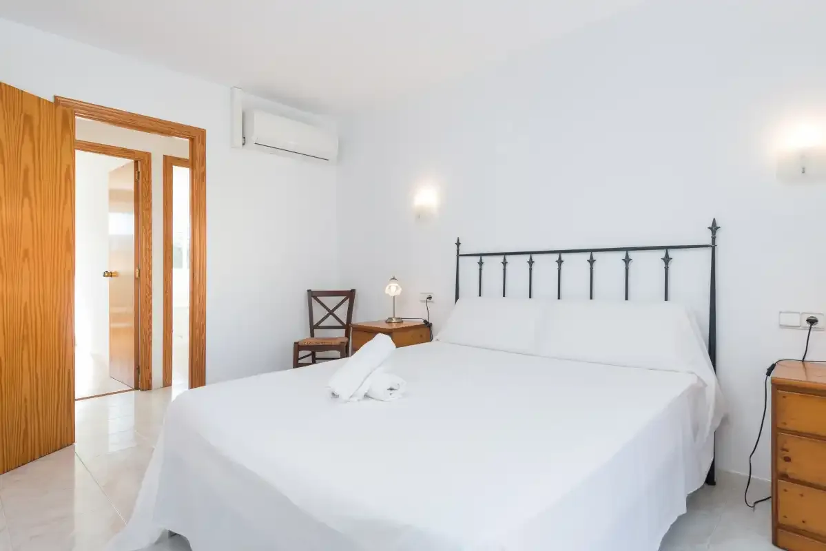 A bright bedroom with a large bed and a doorway beside it.