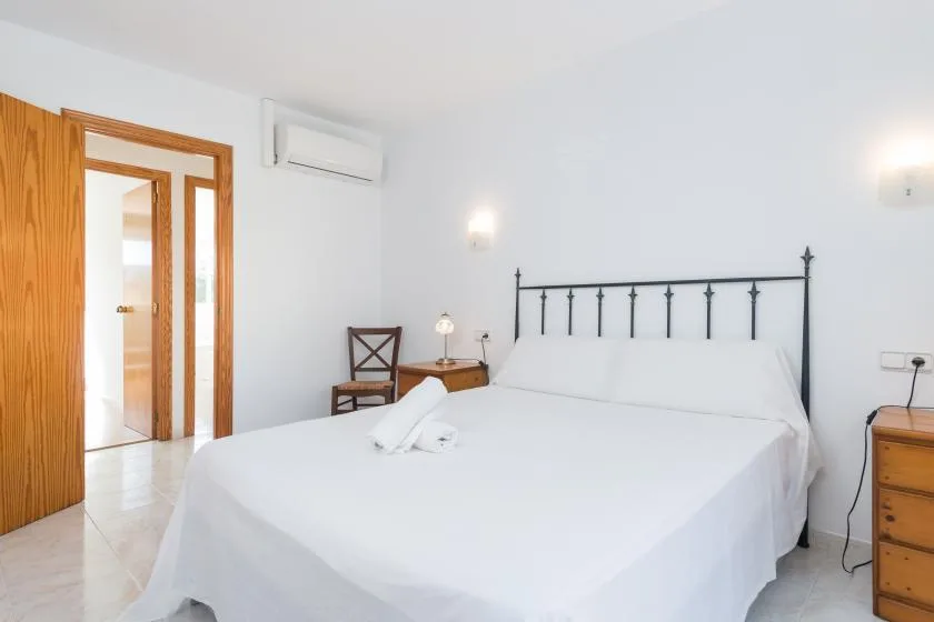 A bright bedroom with a neatly made bed and a black metal headboard.