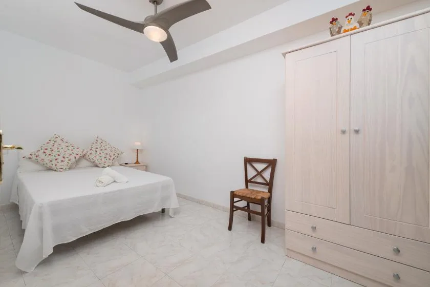 A bedroom with a bed, wooden chair, and large wardrobe.