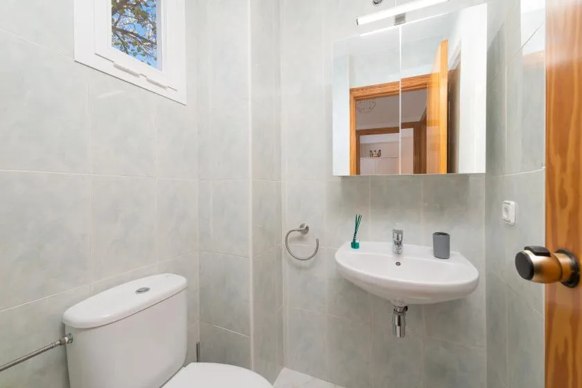 A bright bathroom with a wall-mounted sink and a toilet.