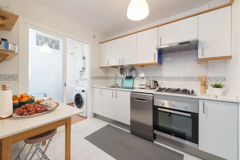 A bright kitchen with white cabinets, a countertop, and a dining table.