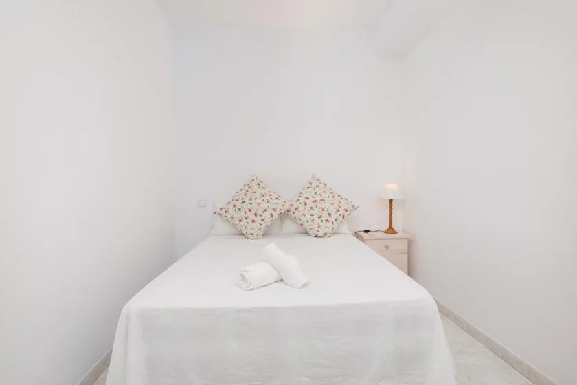 A bright bedroom with a neatly made bed and patterned pillows.