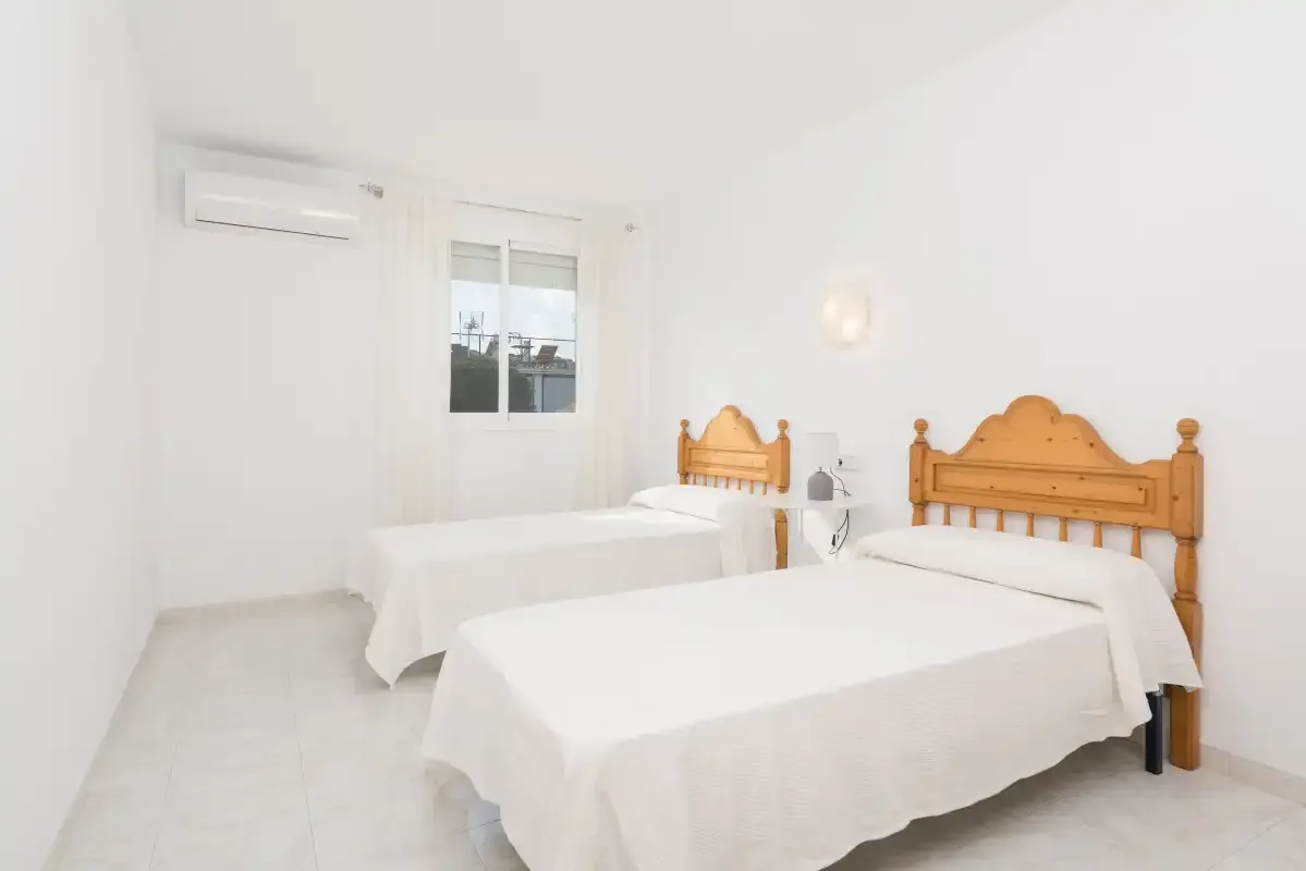 A bright bedroom with two beds and a window.