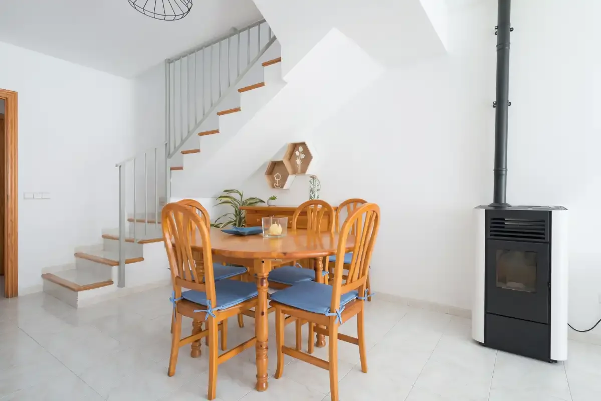 A dining area with a wooden table and seating beneath a staircase.