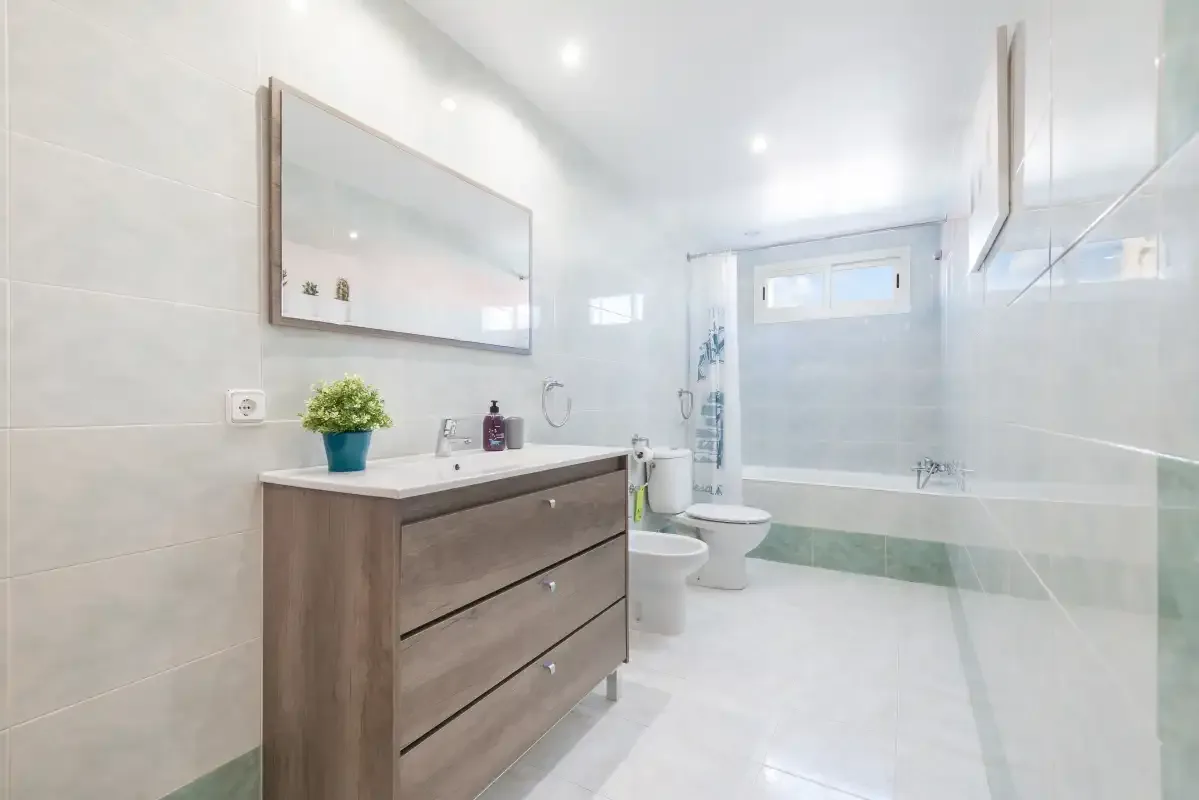 A bright bathroom with a vanity, mirror, and shower.