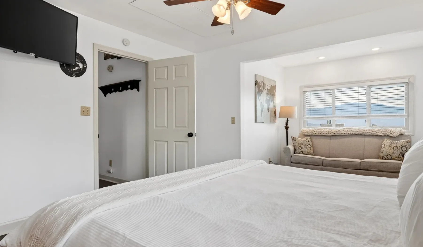 Un dormitorio con una cama y una zona de estar junto a una ventana.