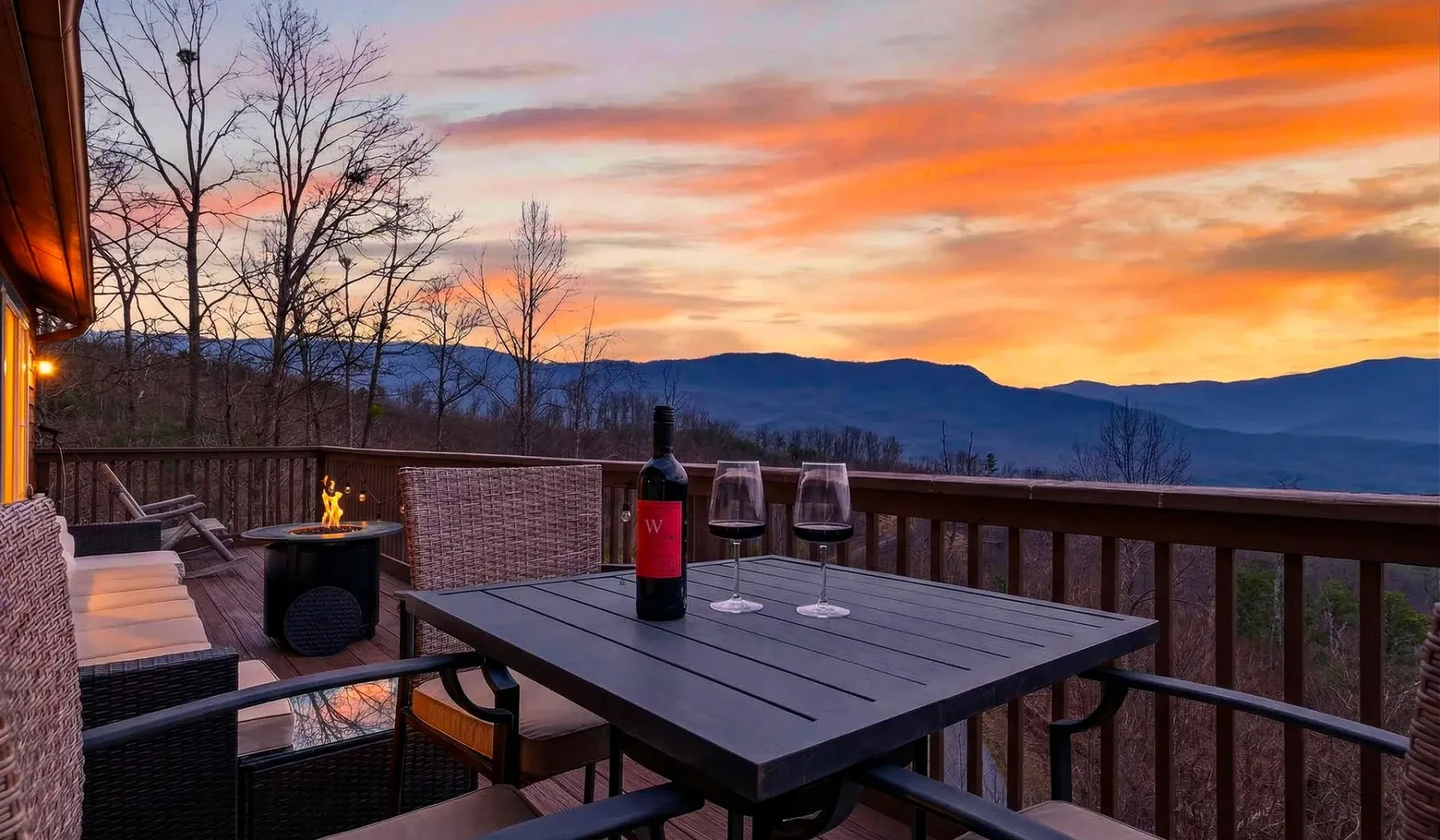 Asientos en una terraza exterior miran hacia montañas bajo un cielo de atardecer.