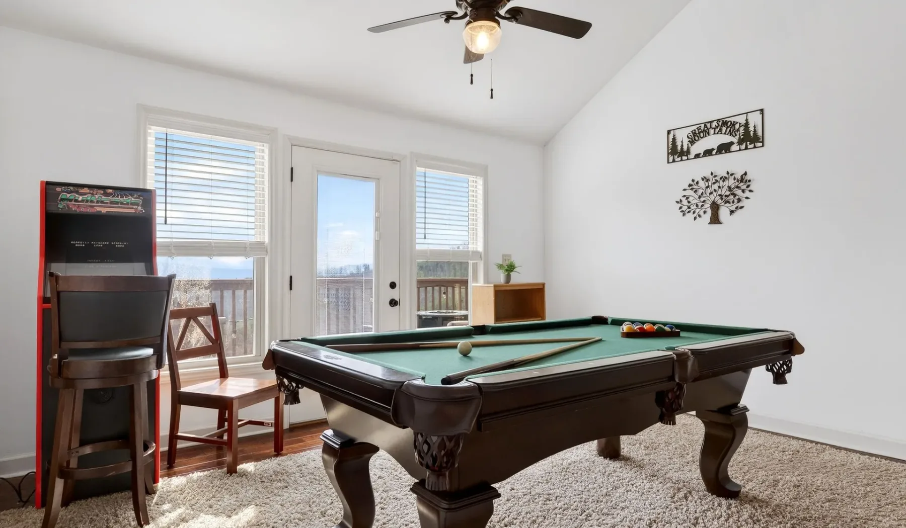 Una luminosa sala de juegos con una mesa de billar de paño verde y ventanas grandes.