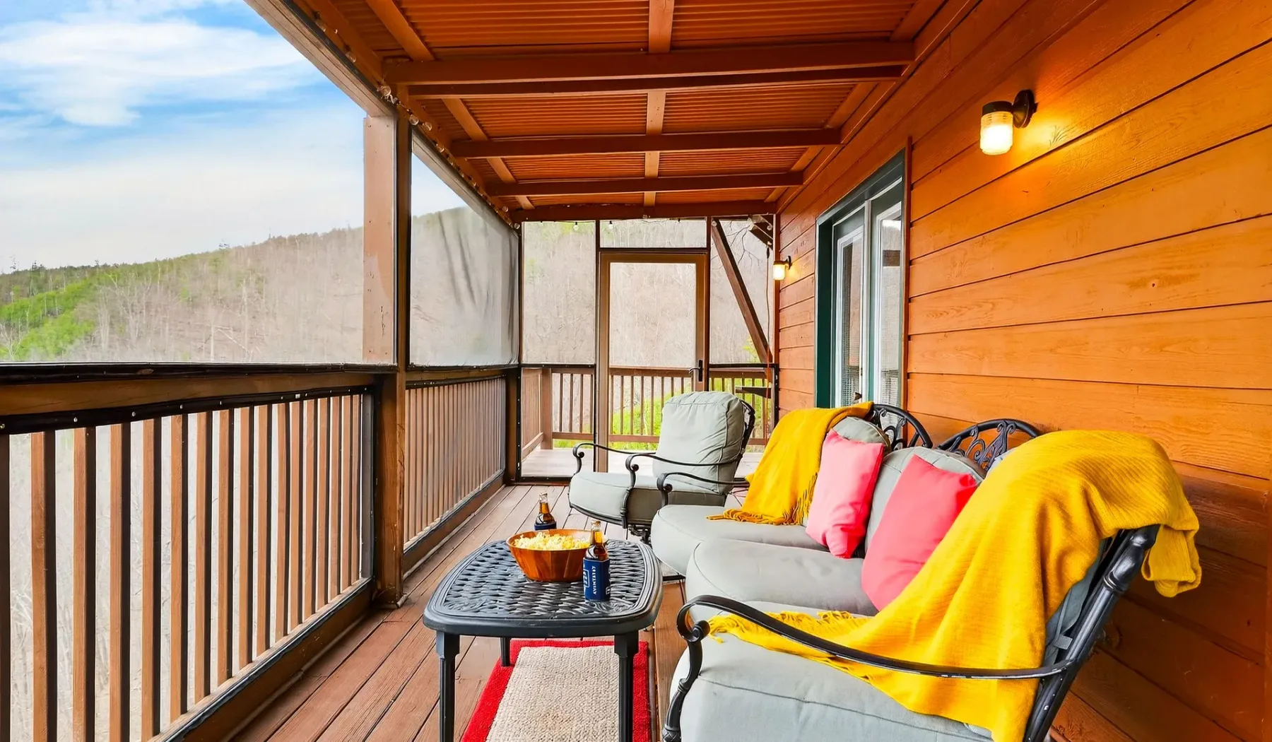 Una terraza cubierta de madera con asientos acolchados y una mesa pequeña.