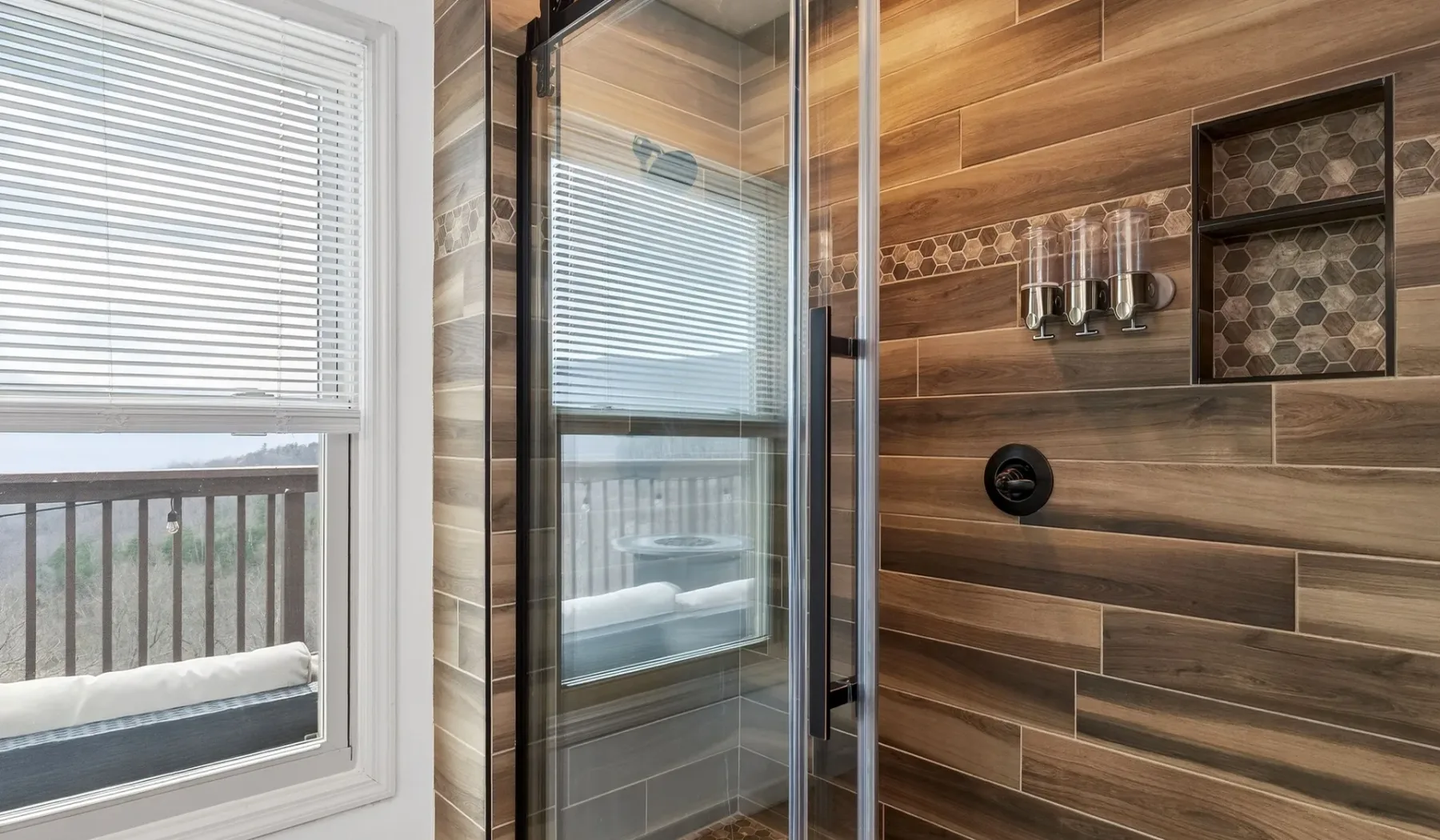 Una ducha de baño con azulejos junto a una ventana con persianas.