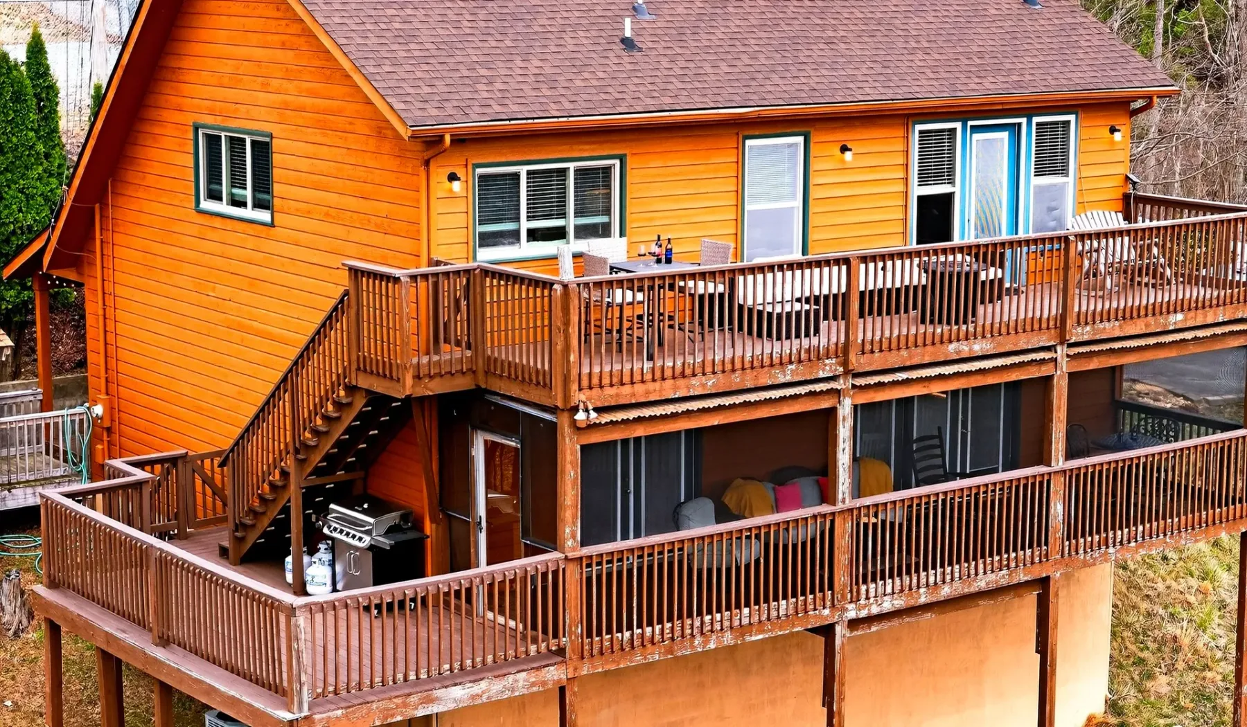 Una casa naranja de madera con amplias terrazas elevadas y escaleras exteriores.