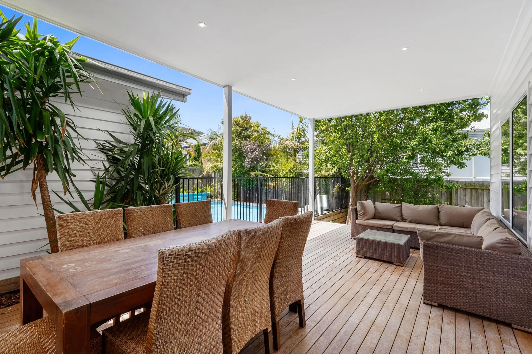 Covered outdoor patio with dining and lounge seating overlooking a swimming pool.