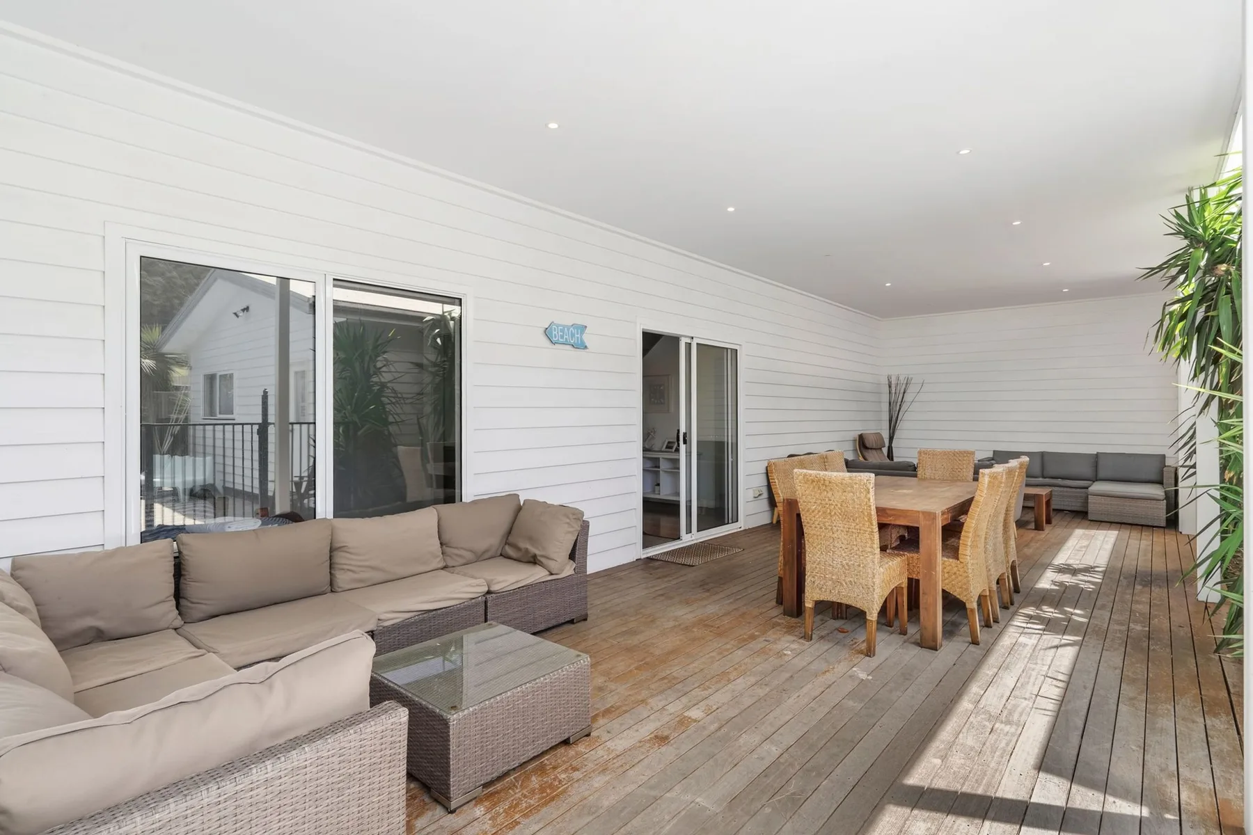 A covered outdoor seating and dining area with sliding glass doors.