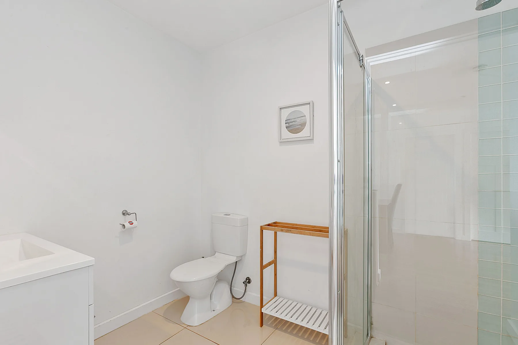 A bright bathroom with a toilet, sink, and glass shower.