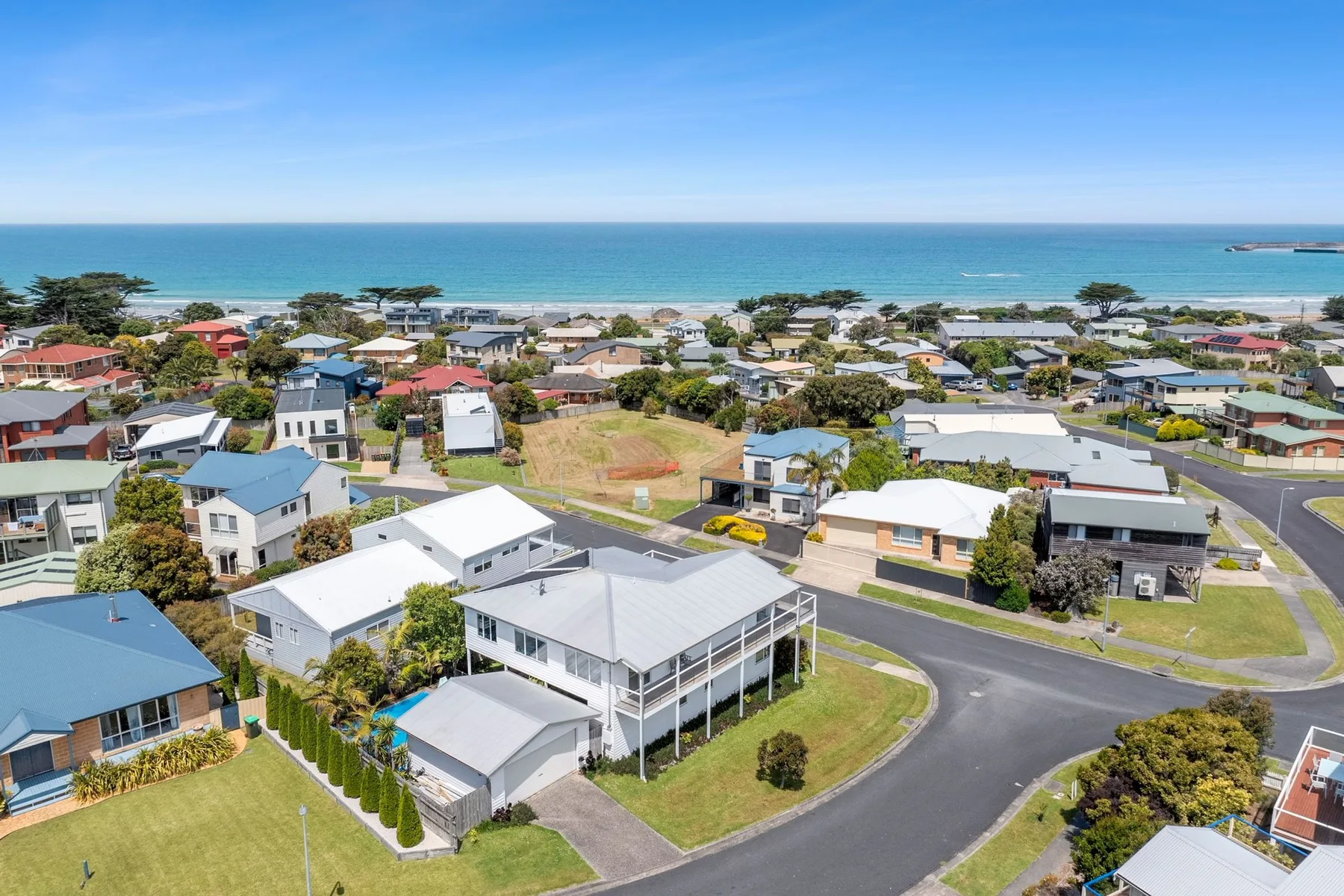 Aerial view of a coastal neighborhood with houses, roads, and the ocean.