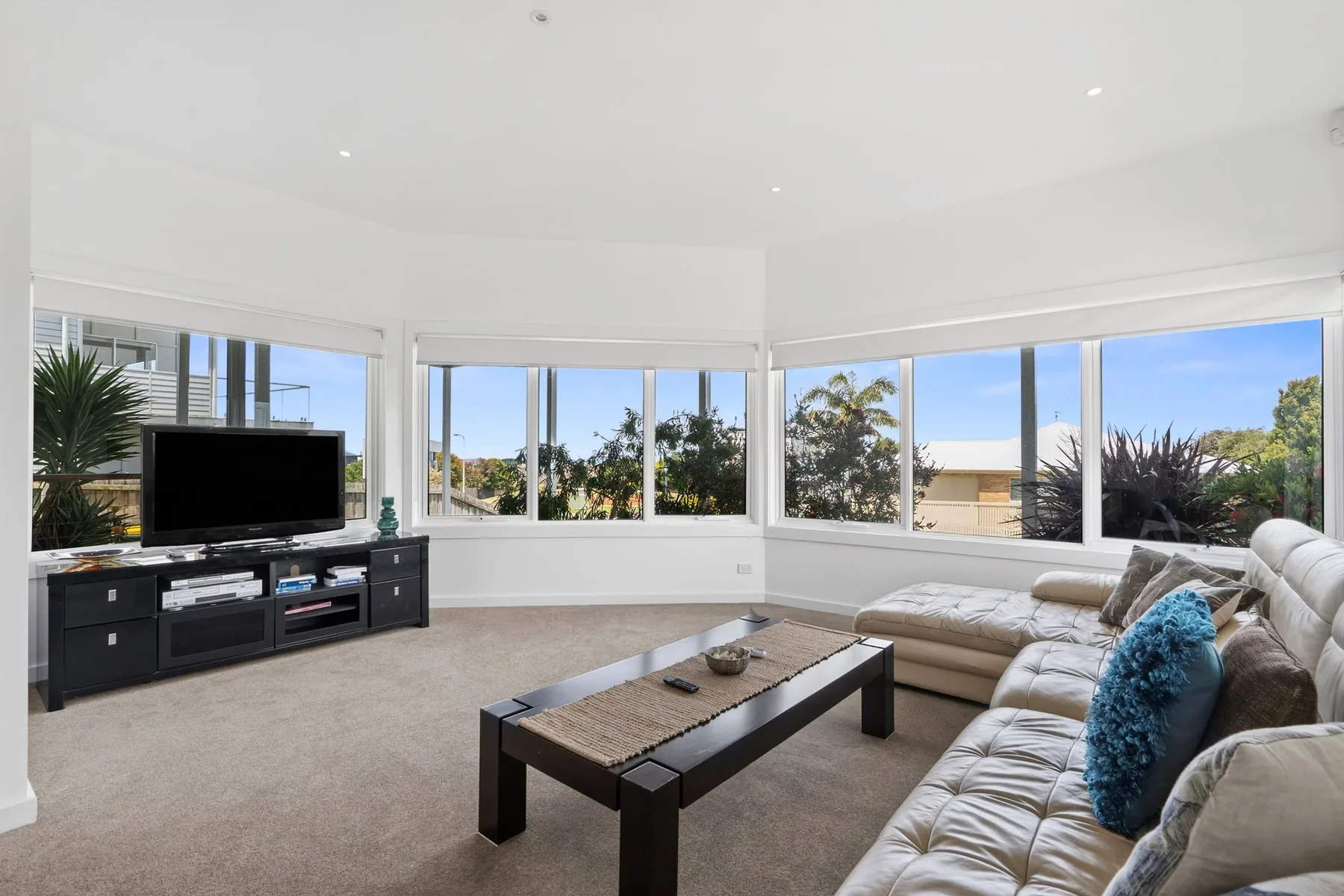 A bright living room with large windows, a television, and seating.