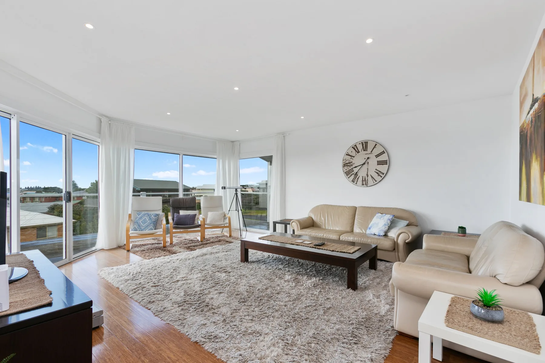 A bright living room with seating around a coffee table and large windows.