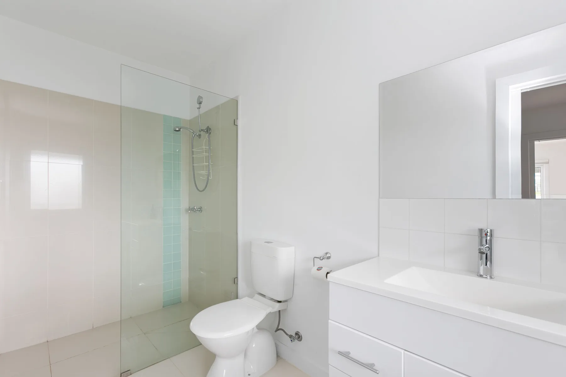 A bright bathroom with a shower, toilet, and sink.