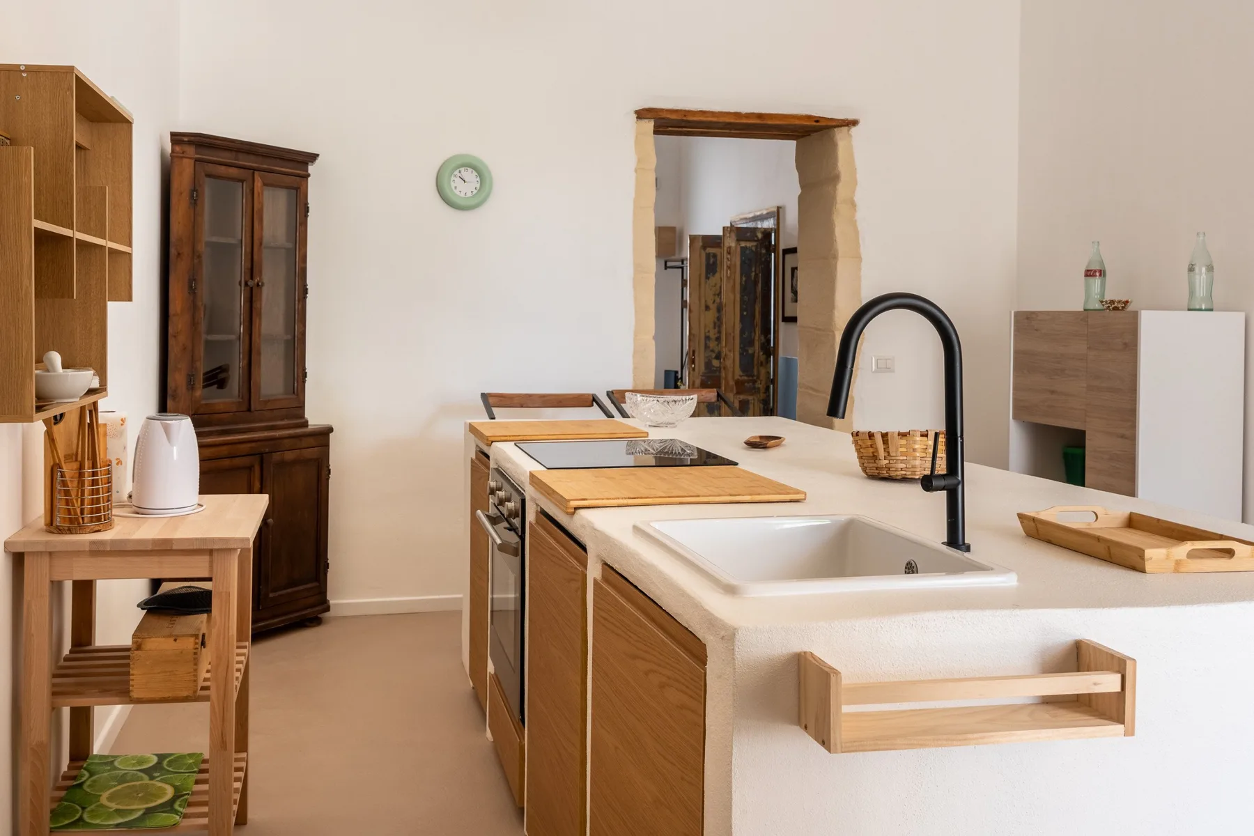A kitchen with a large white island, sink, and black faucet.