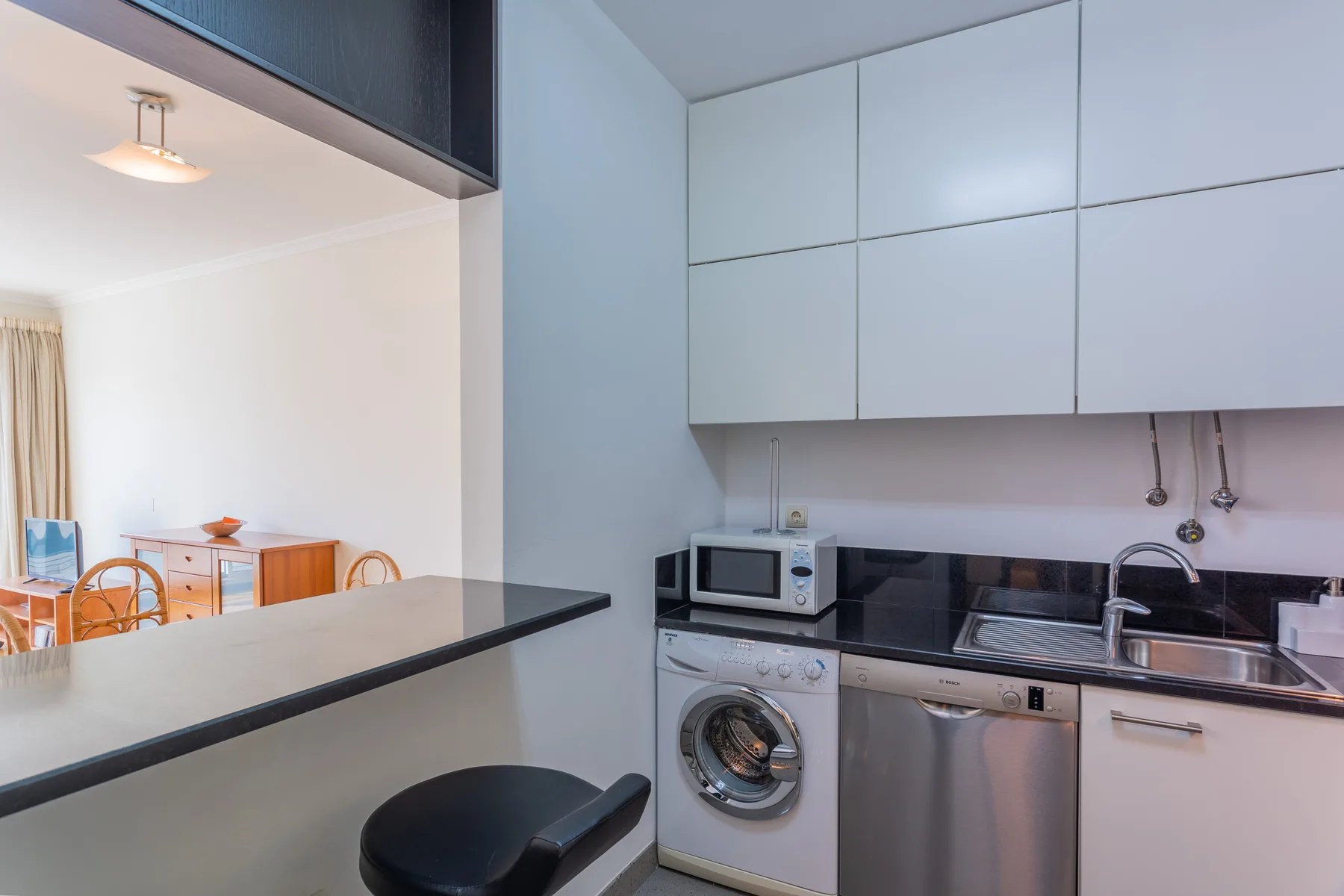 A compact kitchen area with a washing machine, sink, and countertop.